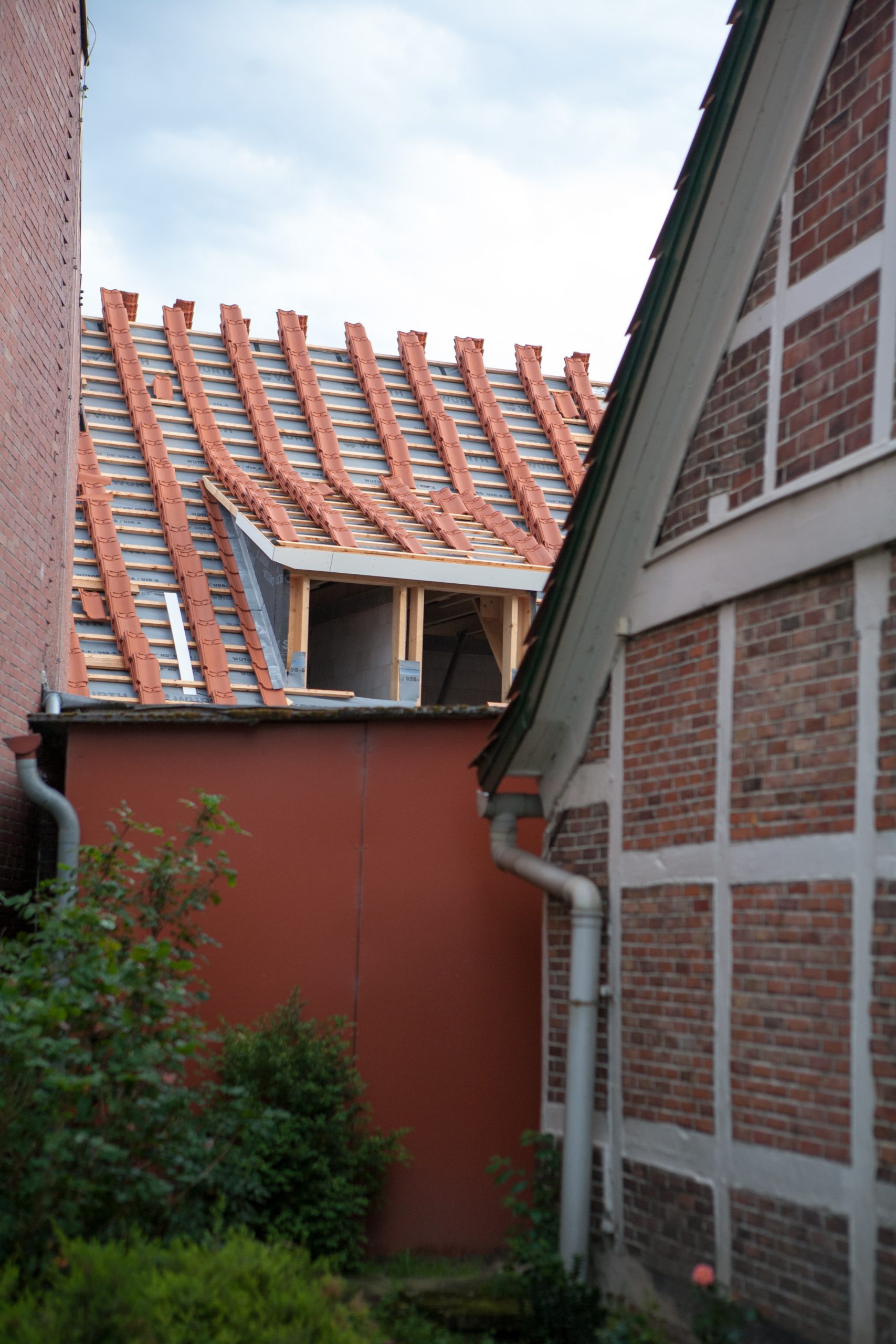 Das Foto zeigt ein Dorf mit Altbauten und im Hintergrund ein Neubau.